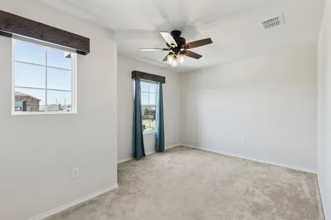 an empty room with windows and fan