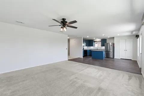 a view of a big room with a chandelier fan and windows