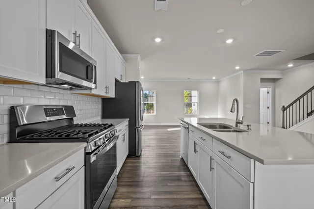 a open kitchen with white cabinets and wooden floor