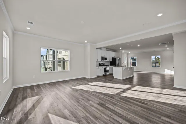 a view of an empty room with wooden floor and window