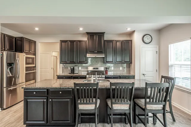 a kitchen with granite countertop a stove a sink and a refrigerator