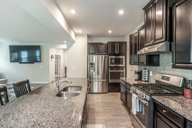 a kitchen with stainless steel appliances granite countertop a stove top oven a sink dishwasher a dining table and chairs