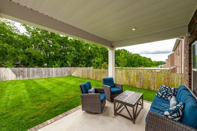 a view of a patio with couches chairs potted plants and a yard