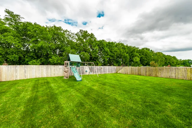 a view of a house with a big yard and large trees
