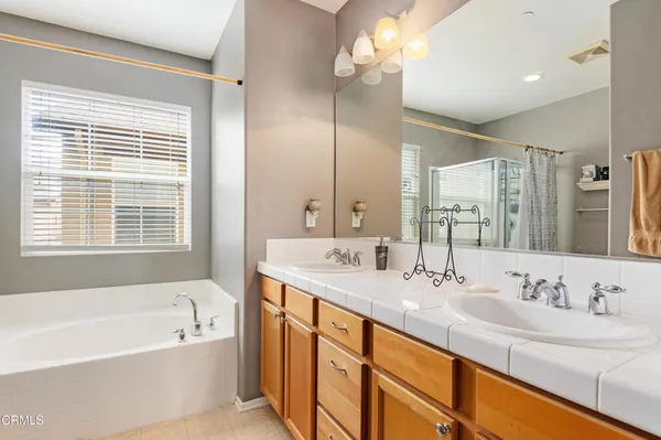a bathroom with a tub a sink double vanity and a mirror