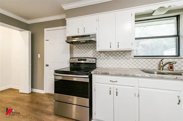 a kitchen with granite countertop a sink cabinets stainless steel appliances and a window