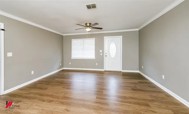 an empty room with wooden floor chandelier and windows