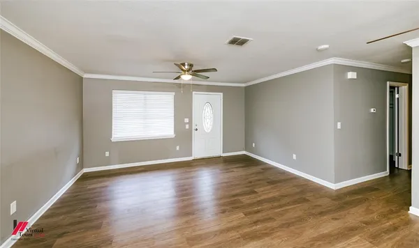 a view of an empty room with wooden floor and a window
