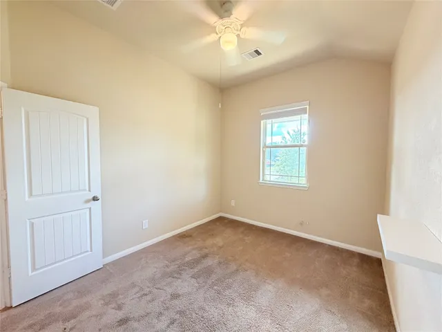 an empty room with a window and a fan