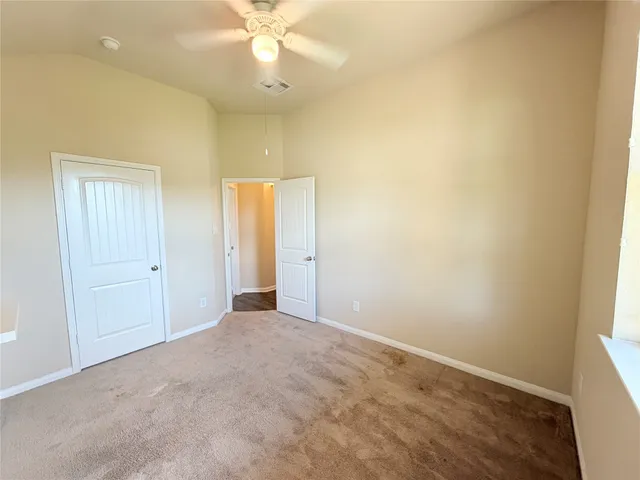 an empty room with a ceiling fan and a window