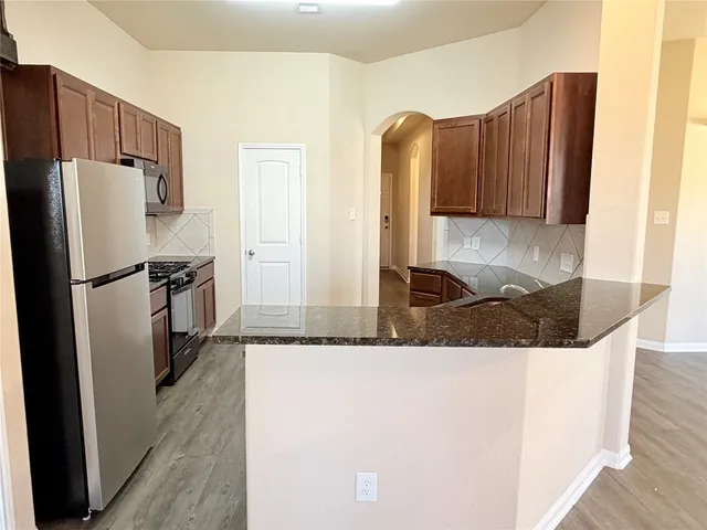 a kitchen with stainless steel appliances granite countertop a refrigerator and a stove