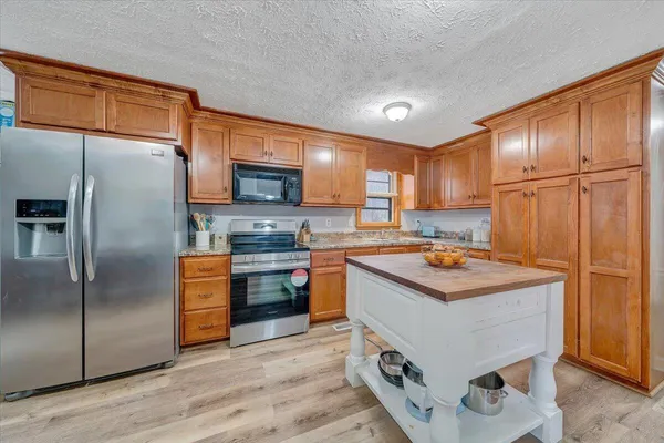 a kitchen with kitchen island granite countertop wooden cabinets and stainless steel appliances