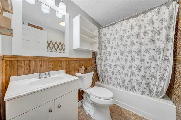 a bathroom with a sink a toilet and shower curtain