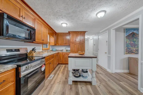 a kitchen with stainless steel appliances granite countertop a stove top oven a sink dishwasher and cabinets with wooden floor