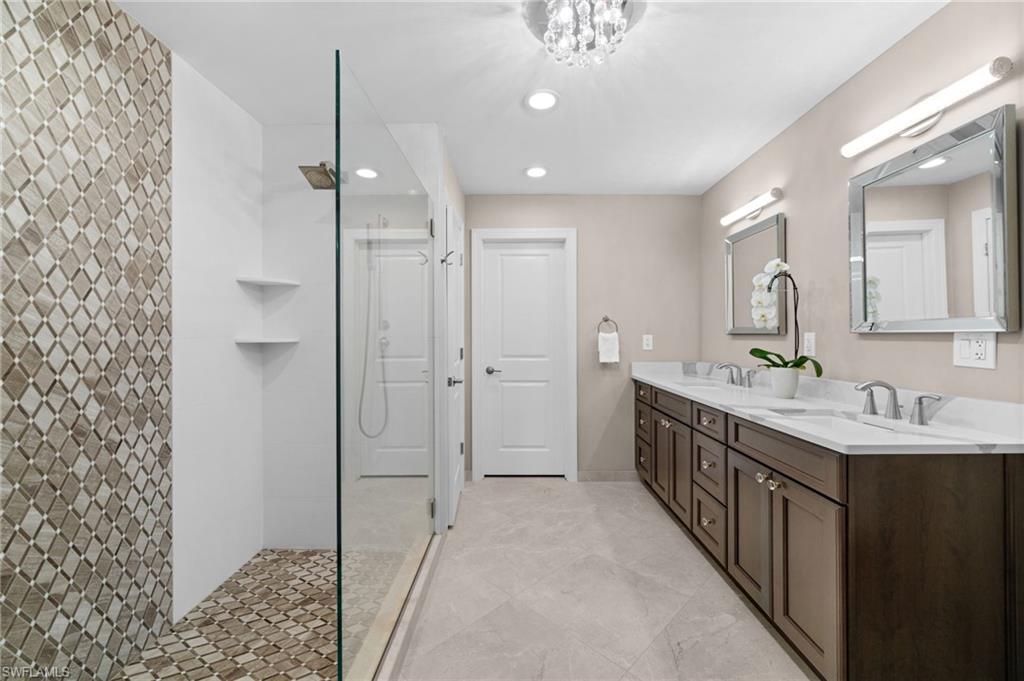 1960 Imperial Golf Course Boulevard Naples, FL 34110 - Photo 14 of 38 Spa-inspired primary bath with quartz countertops, dual vanities, custom tile shower, and solid wood cabinetry