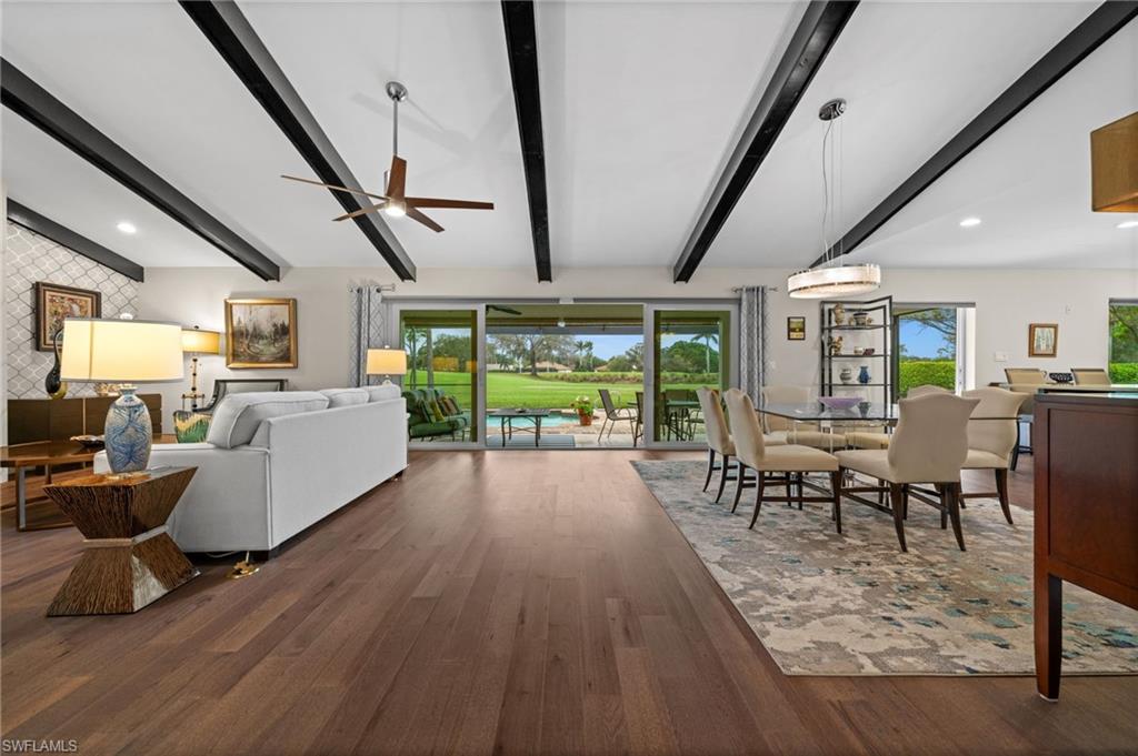 1960 Imperial Golf Course Boulevard Naples, FL 34110 - Photo 2 of 38 Open-concept living and dining with vaulted ceilings, exposed beams, engineered hickory hardwood floors, and seamless indoor-outdoor flow to the lanai and golf course