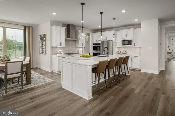 a kitchen with stainless steel appliances kitchen island granite countertop a table chairs and a refrigerator