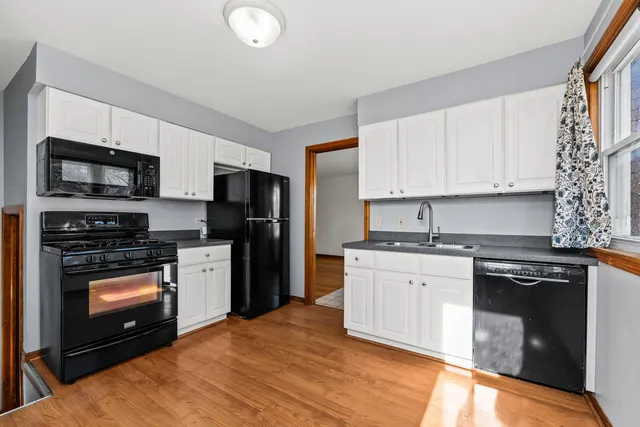 a kitchen with stainless steel appliances granite countertop a stove top oven a sink and dishwasher a refrigerator with wooden floor