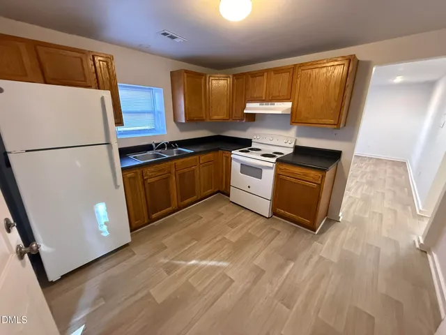 a kitchen with granite countertop a refrigerator a sink a stove a washer dryer and a refrigerator