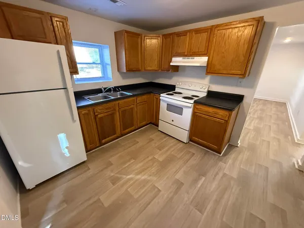 a kitchen with granite countertop a refrigerator sink and cabinets