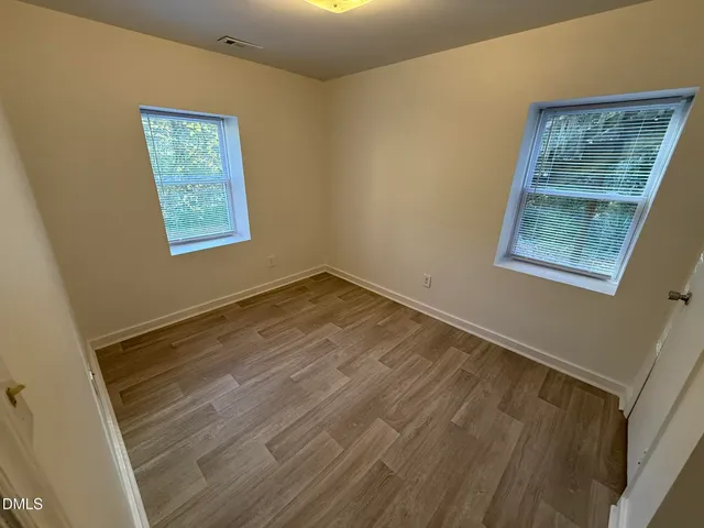 a view of an empty room with a window and wooden floor