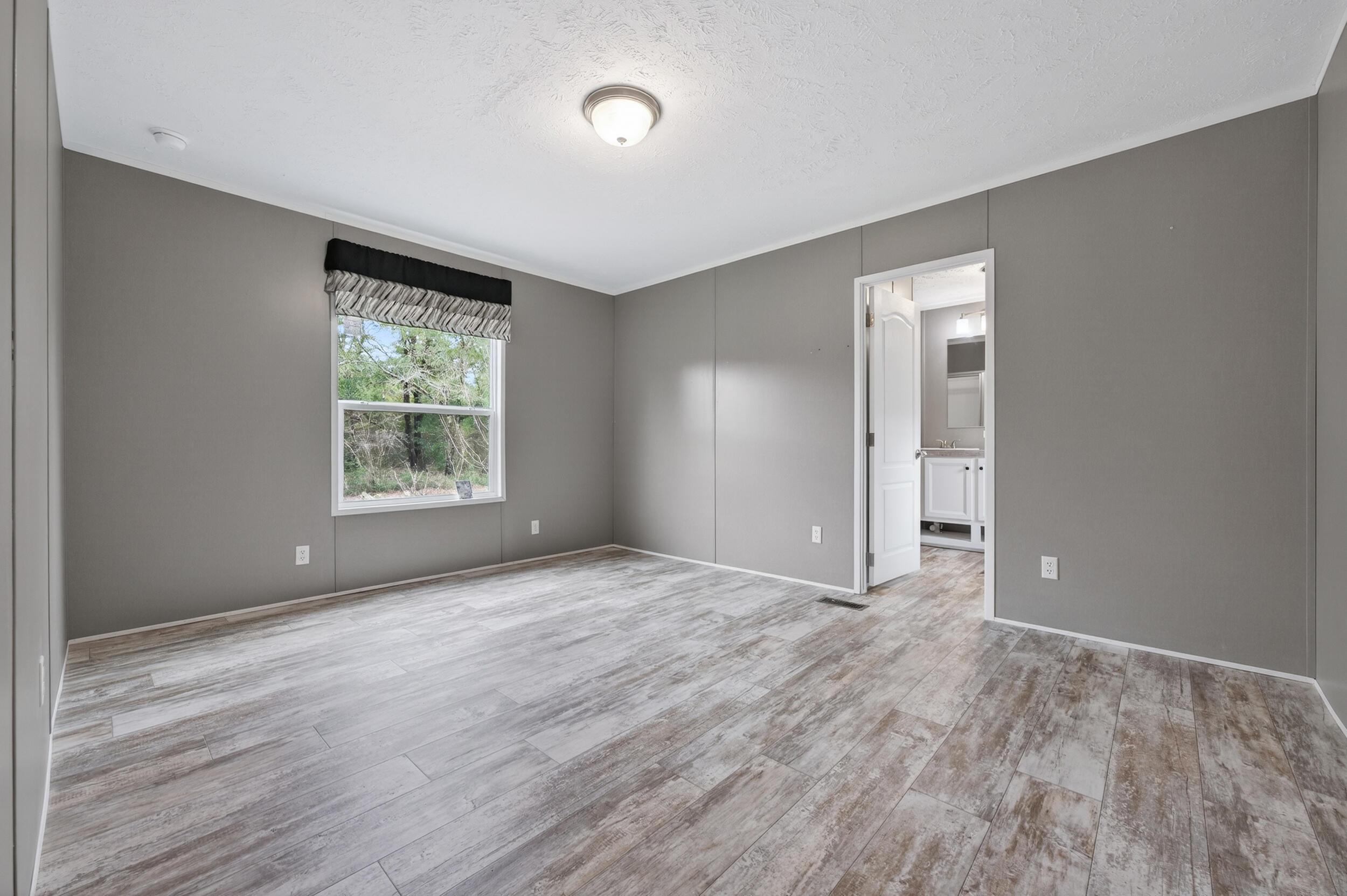 4528 Bryant Bridge Cutoff Road Holt, FL 32564 - Photo 17 of 63 a view of an empty room with wooden floor and a window