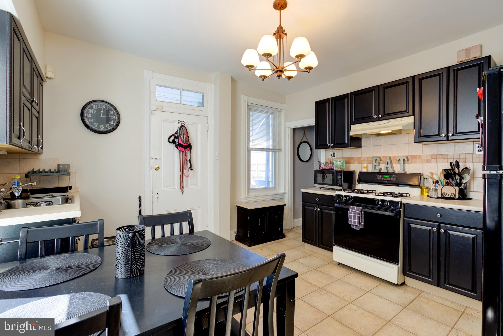 4360 Pechin Street Philadelphia, PA 19128 - Photo 13 of 40 a kitchen with stainless steel appliances granite countertop a stove top oven a sink dishwasher and a dining table with cabinets