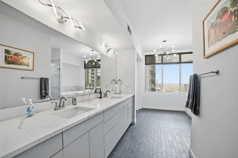 a bathroom with a double vanity sink a mirror a bathtub and shower