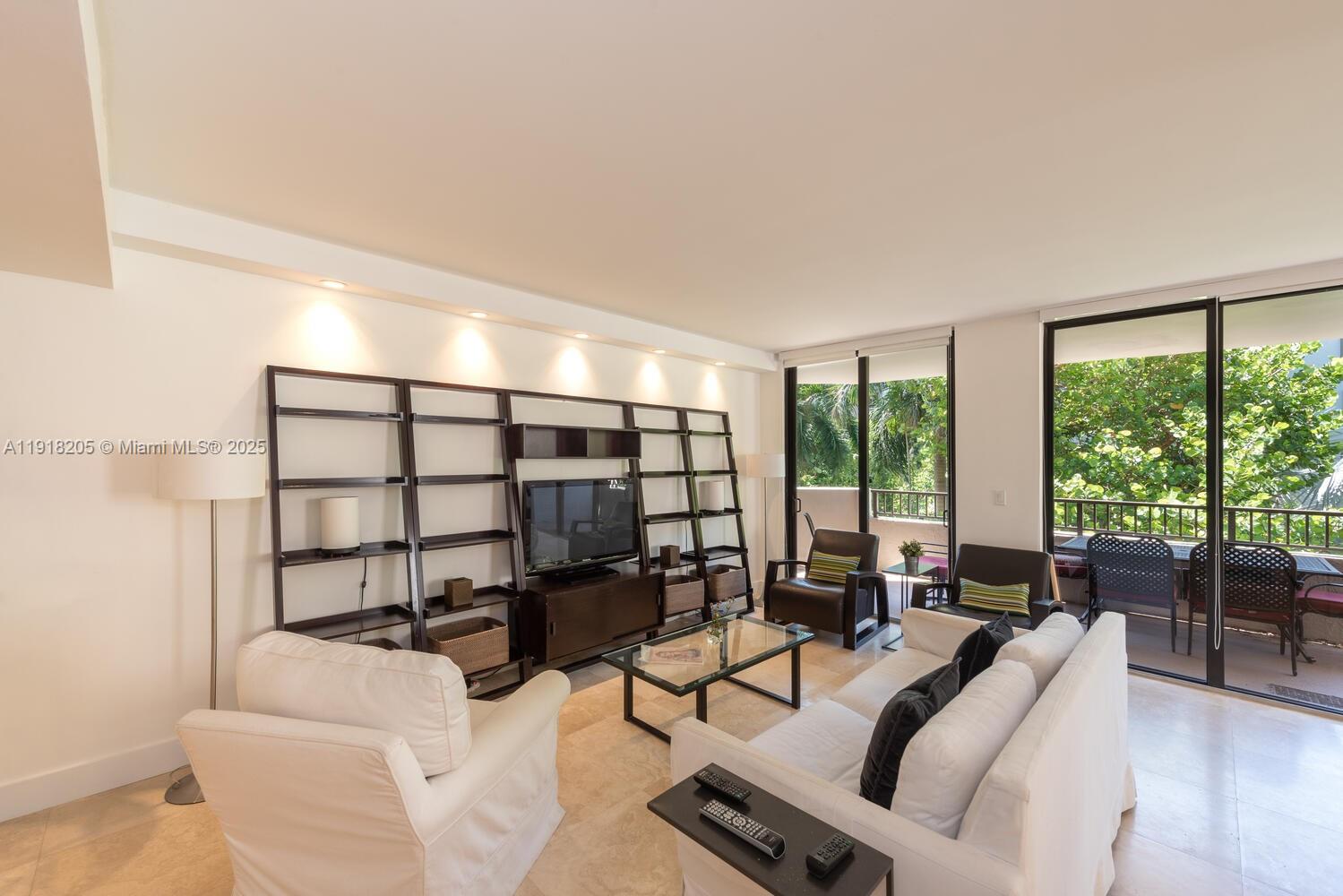 141 Crandon Boulevard, Unit 235 Key Biscayne, FL 33149 - Photo 6 of 25 a living room with furniture a lamp wooden floor and a large window