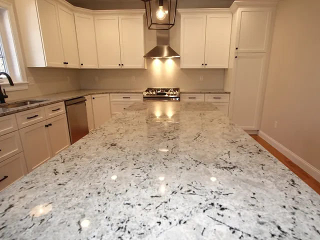 a kitchen with granite countertop white cabinets and stainless steel appliances