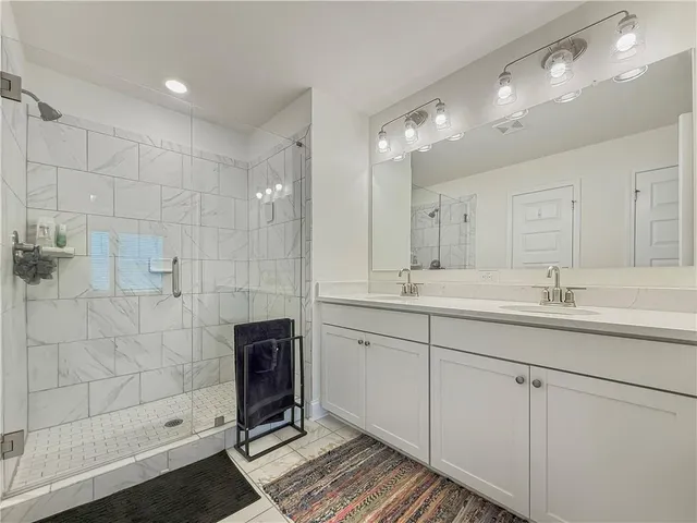 a spacious bathroom with double sink shower and two mirror
