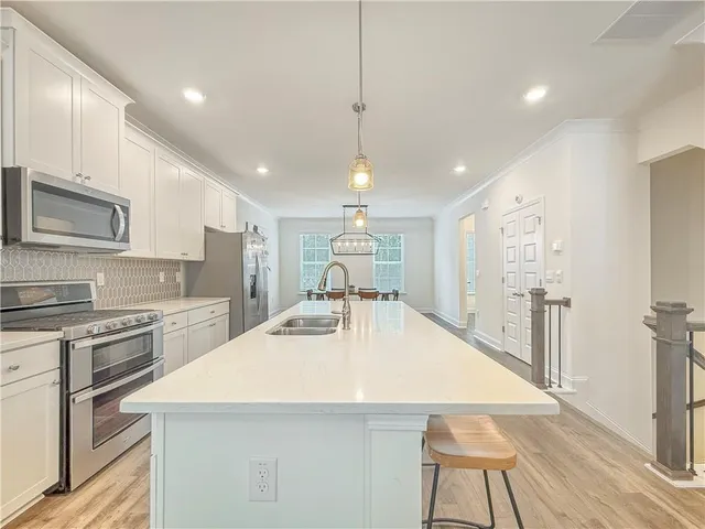 a large kitchen with kitchen island a stove a sink a refrigerator and cabinets