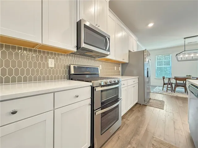 a kitchen with stainless steel appliances a stove a sink cabinets and a wooden floor