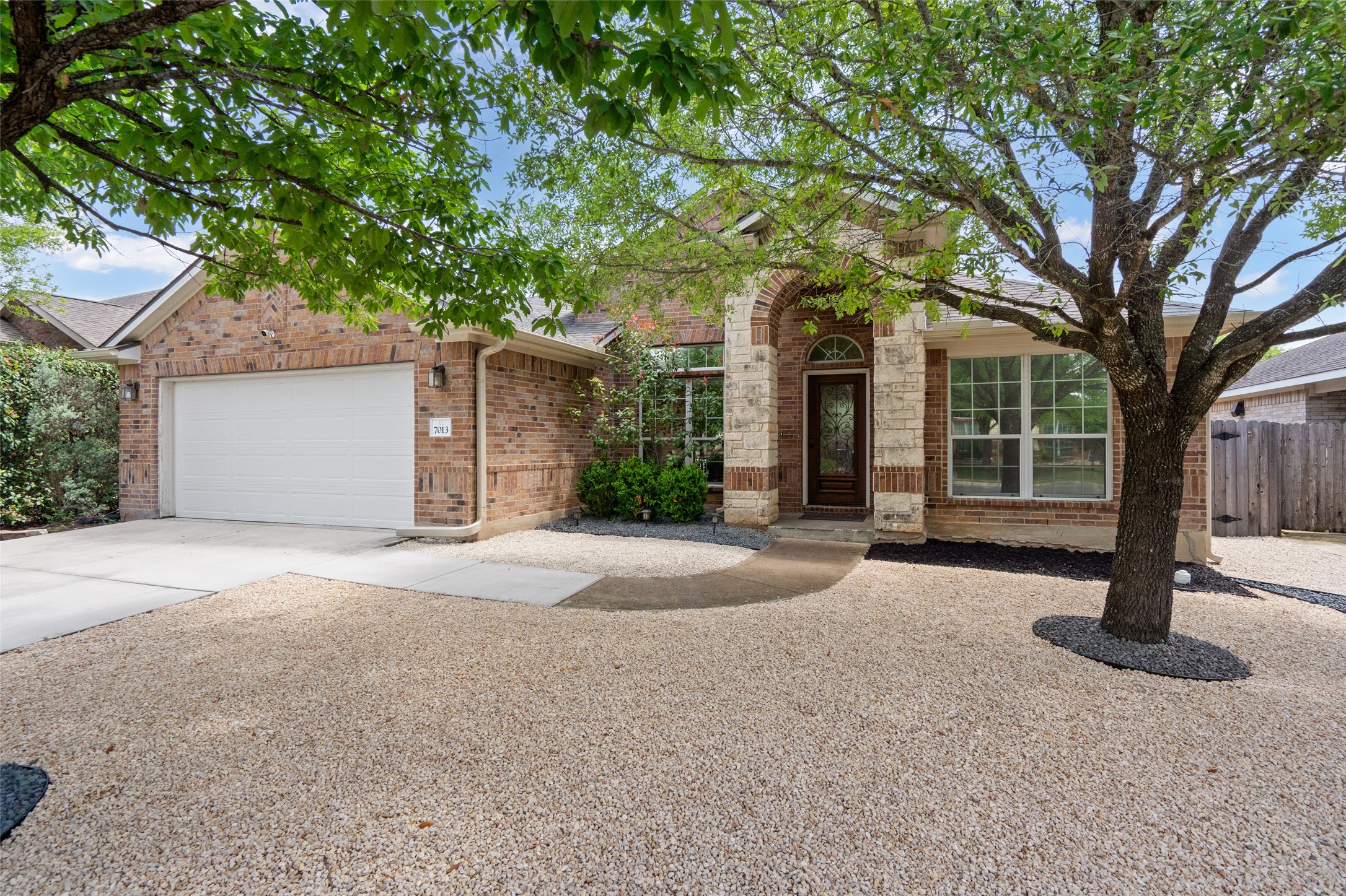 The property features a brick exterior with stone accents, a two-car garage, and a covered entryway