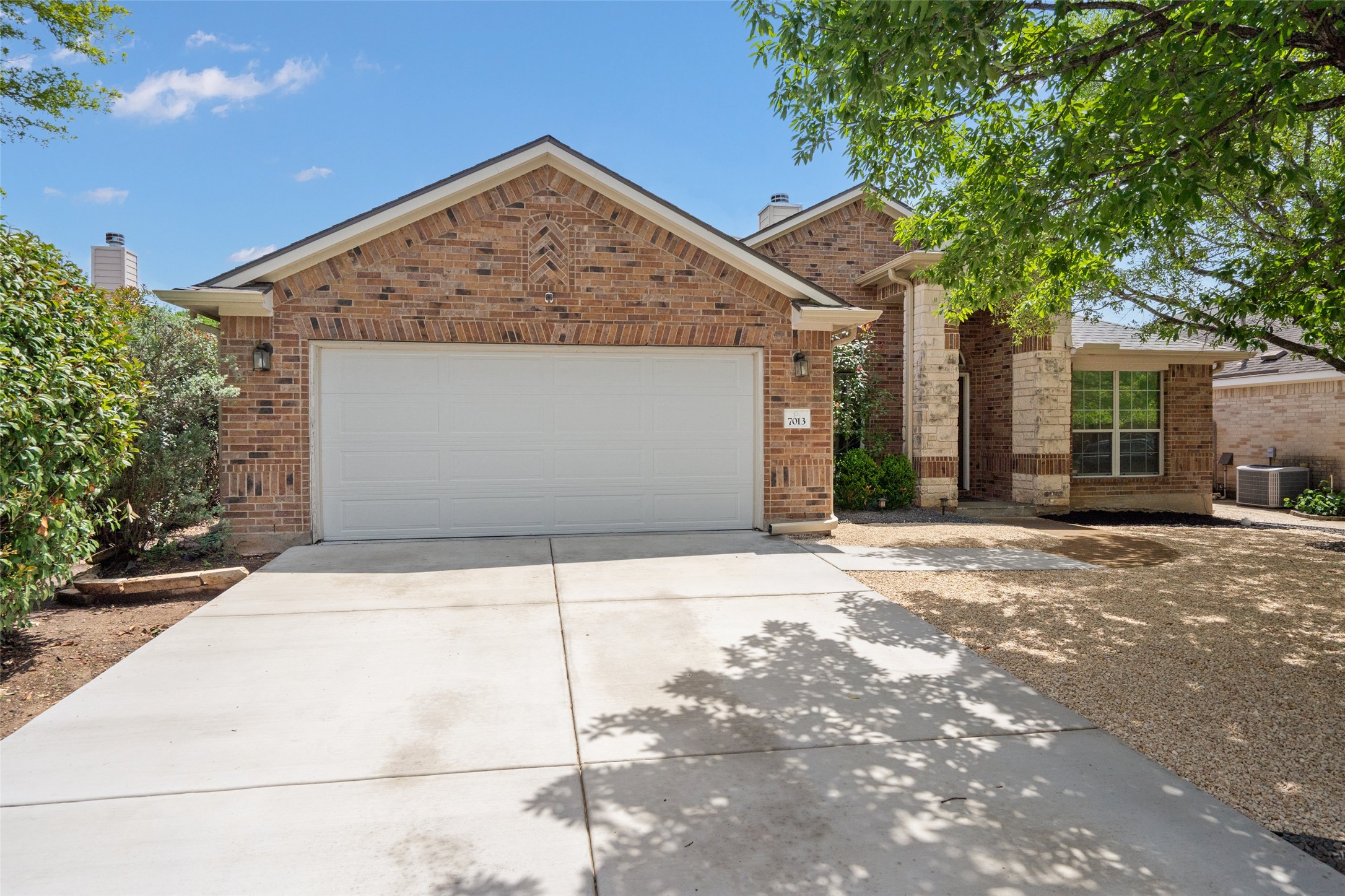 7013 Cromarty Lane Austin, TX 78754 - Photo 3 of 37 The property features a brick and stone facade, a two-car garage, and a concrete driveway