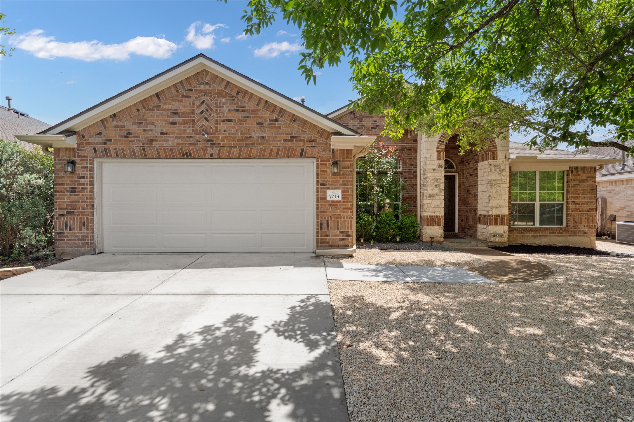 7013 Cromarty Lane Austin, TX 78754 - Photo 4 of 37 The property features an appealing brick and stone facade, a two-car garage, and a concrete driveway