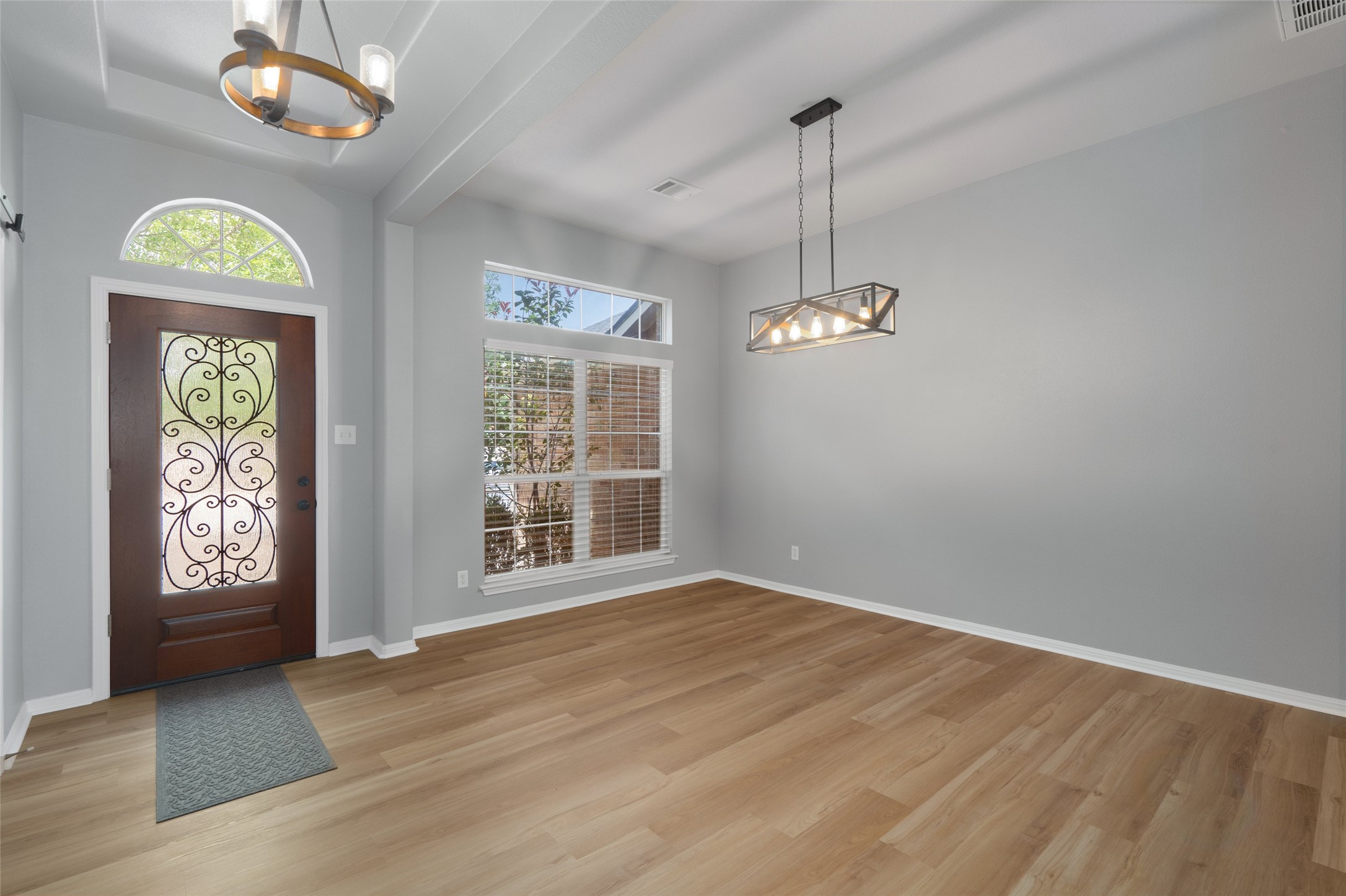 7013 Cromarty Lane Austin, TX 78754 - Photo 5 of 37 The entryway features a decorative wooden door with an arched transom window, light wood flooring, and a modern chandelier