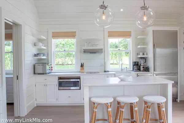 a kitchen with granite countertop a stove chairs and chandelier