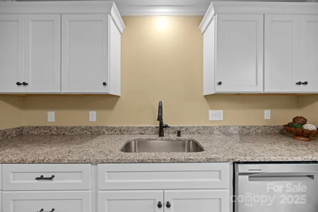 a kitchen with granite countertop white cabinets and a sink