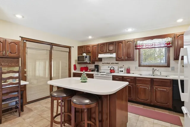 a kitchen with a sink a stove a refrigerator cabinets and dining table