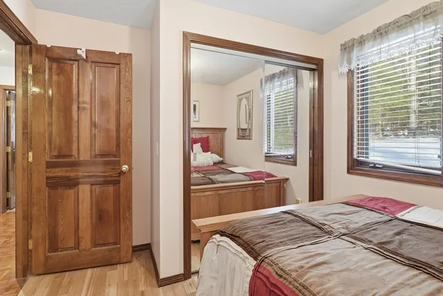 a bedroom with a bed and dresser with wooden floor