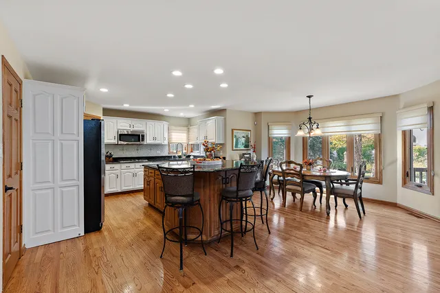 a kitchen with stainless steel appliances granite countertop a refrigerator and a stove top oven with wooden floor