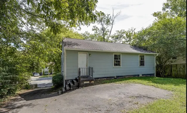 a view of a house with a yard and large tree
