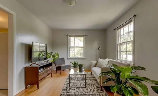 a living room with furniture floor to ceiling window and a flat screen tv