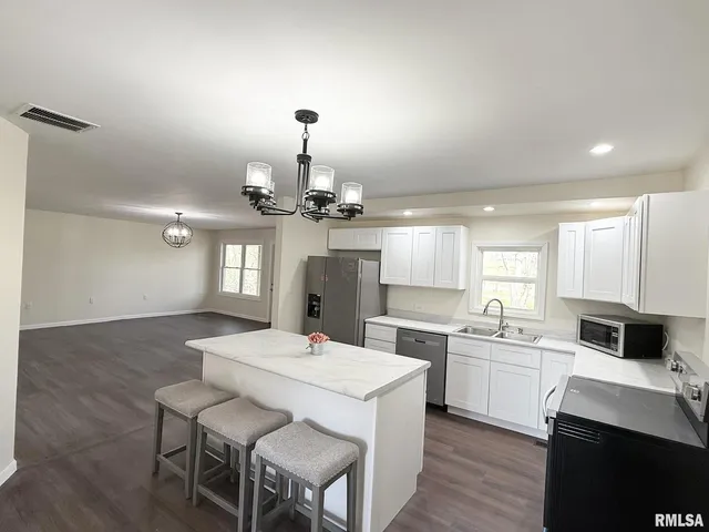 a kitchen with a sink dishwasher a stove a microwave oven with a dining table and chairs