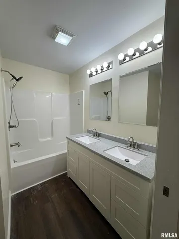 a bathroom with a tub a double vanity sink and a mirror