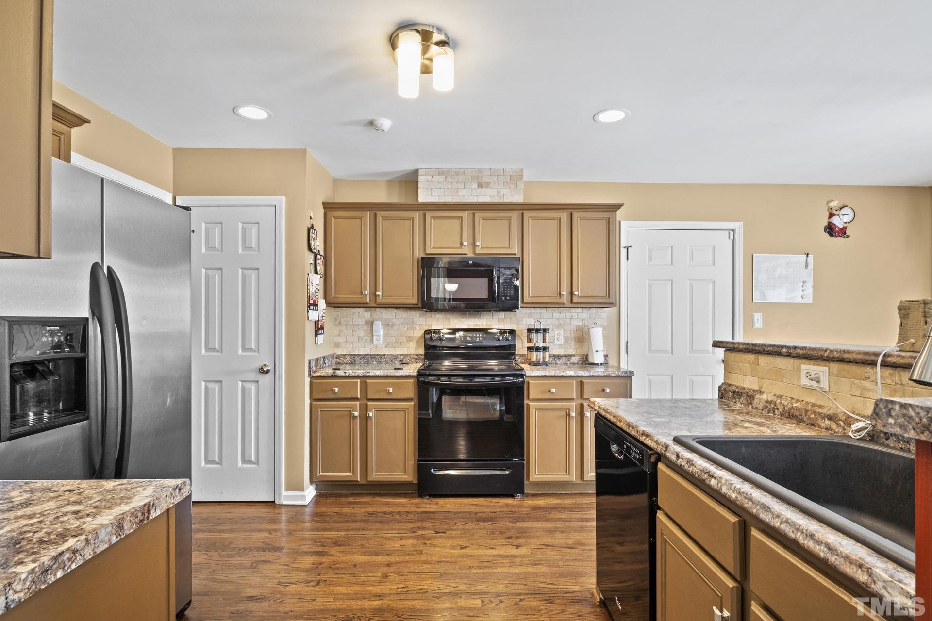 117 Mendel Drive Smithfield, NC 27577 - Photo 11 of 39 a kitchen with stainless steel appliances granite countertop a stove top oven a sink and a refrigerator