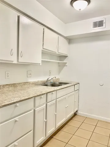 a kitchen with granite countertop white cabinets and a sink