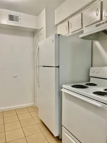 a white refrigerator freezer and a stove sitting inside of a kitchen