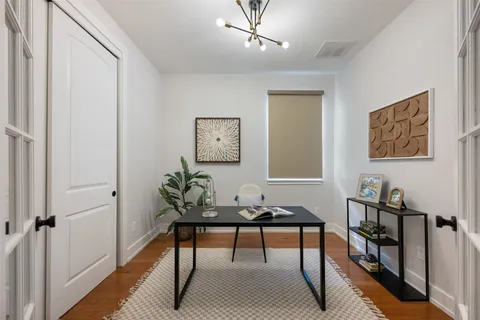 a living room with a bed furniture flat screen tv and a large window